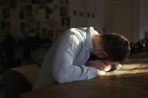 Young man sitting at kitchen table with his head down — Stock Photo