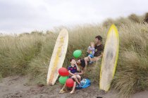 Famille avec deux garçons sur la plage avec planches de surf — Photo de stock