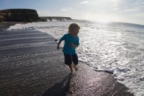 Хлопчик грає в хвилях на пляжі — стокове фото