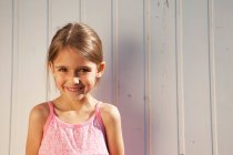 Little girl in front of a wooden wall — Stock Photo