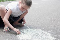 Mädchen zeichnet Sonne mit Kreide auf Bürgersteig — Stockfoto