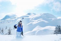 Uomo che trasporta snowboard nella neve, focus selettivo — Foto stock