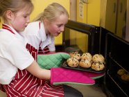 Girls taking bread out of the oven — Stock Photo