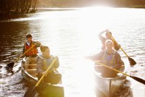 Friends rowing canoes on still lake — Stock Photo