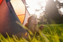 Teenage girl laying in tent at campsite — Stock Photo