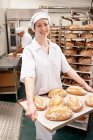 Шеф-повар несет поднос с хлебом на кухне — стоковое фото