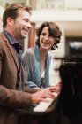 Пара, играющая вместе на пианино дома — стоковое фото