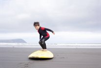 Garçon pratiquant sur planche de surf sur la plage — Photo de stock