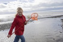 Junges Mädchen läuft mit Fischernetz am Strand — Stockfoto