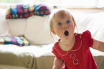 Toddler girl gasping in living room — Stock Photo