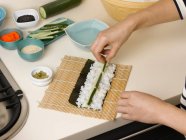 Mujer preparando rollo de sushi - foto de stock