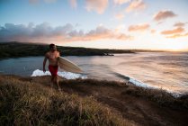 Surfer carrying board on beach — Stock Photo