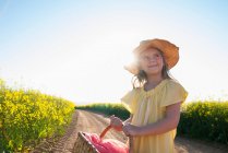Girl carrying basket on dirt road — Stock Photo