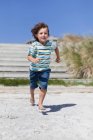 Garçon courir sur la plage de sable fin — Photo de stock