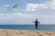Хлопчик літає повітряним змієм на пляжі — стокове фото