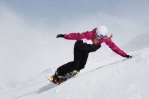 Giovane donna snowboard giù per il pendio — Foto stock