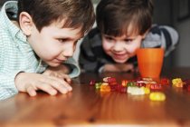Хлопчики грають з цукерками за столом — стокове фото