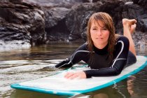 Donna sdraiata sulla tavola da surf in acqua — Foto stock