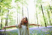 Девочка слушает музыку в наушниках в лесу — стоковое фото