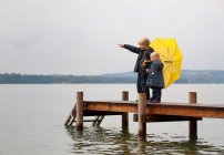 Crianças com guarda-chuva amarelo na doca — Fotografia de Stock