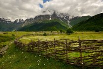 Hand woven fence and distant mountains — Stock Photo
