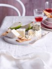 Cheese with fruit and crackers on board — Stock Photo
