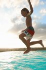 Boy jumping mid air into swimming pool, Buonconvento, Tuscany, Italy — Stock Photo