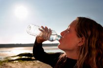 Женщина пьет воду в гидрокостюме — стоковое фото