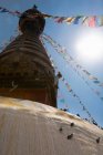 Drapeaux de prière sur la tour du temple à la lumière du soleil — Photo de stock