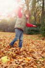 Garçon jouer dans les feuilles d'automne — Photo de stock