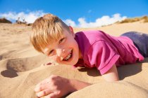 Светловолосый мальчик лежит на пляже — стоковое фото