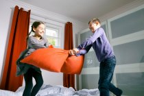 Дети борются на подушках на кровати — стоковое фото
