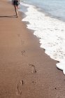Вид ззаду на жіночі сліди на піщаному пляжі — стокове фото