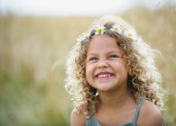 Young girl laughing with daisies in hair — Stock Photo