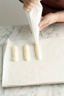 Female hands piping dough on sheet — Stock Photo