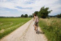 Woman riding bicycle on rural road — Stock Photo