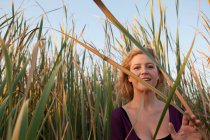 Усміхнена жінка стоїть на пшеничному полі — стокове фото