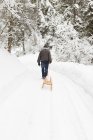 Mann zieht Schlitten in verschneites Feld — Stockfoto