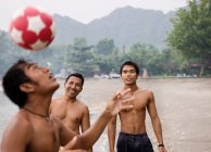Les gars jouent au football sur la plage — Photo de stock