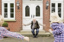 Дедушка приветствует внуков с распростертыми объятьями — стоковое фото