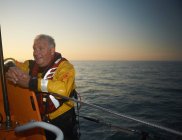 Retrato del hombre maduro tripulando bote salvavidas en el mar - foto de stock