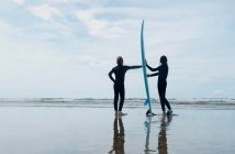 Children holding surf board on beach — Stock Photo