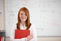 Student holding book in classroom — Stock Photo