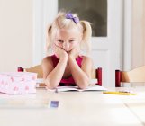 Скучная девушка делает домашнее задание за столом — стоковое фото