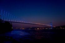 Vista lejana del puente del Bósforo iluminado por la noche, Estambul, Turquía - foto de stock