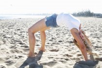 Young woman bending over backwards on beach, Melbourne, Victoria, Australia — Stock Photo