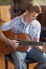 Mann spielt Gitarre im Wohnzimmer — Stockfoto