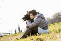 Femme adulte moyenne et son chien assis sur la colline — Photo de stock