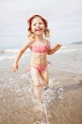 Lächelndes Mädchen spielt in Wellen am Strand — Stockfoto