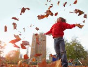 Хлопчик грає з осіннім листям — стокове фото